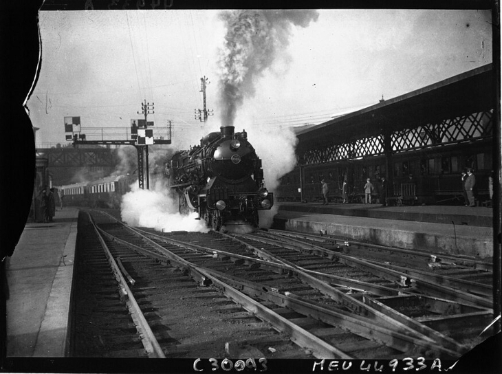 A steam train chuffing through a station