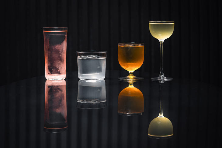 Four classy looking cocktails reflected on a shiny table