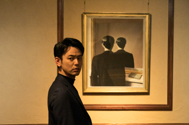 A man standing in front of a picture mounted on a wall