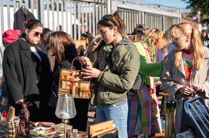 Three women looking at items for sale at a flea market