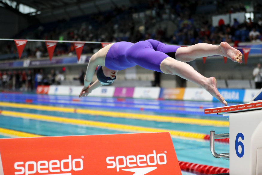 A swimmer diving into the pool at the start of a race