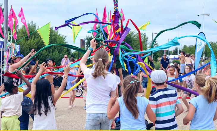 Children playing with colourful streamers around a maypole