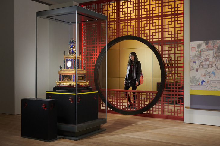 A woman looking at an ornate Chinese clock