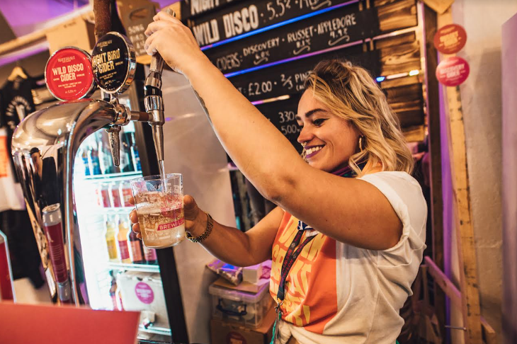 A woman pulling a pint behind a bar