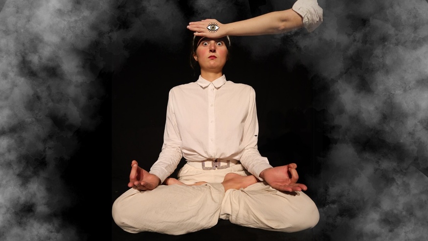 A young woman in the yoga position - a hand with a painted eye on it on her forehead