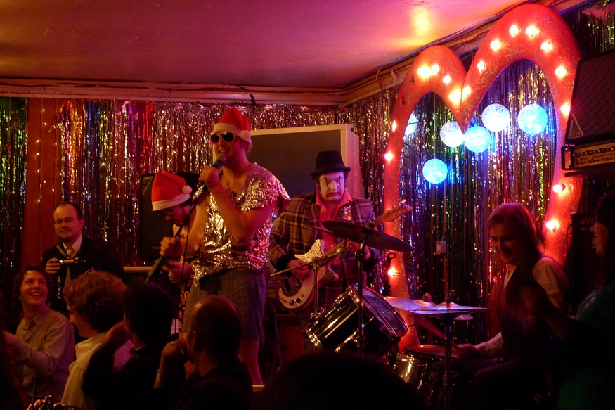 People performing on stage in Xmas hats
