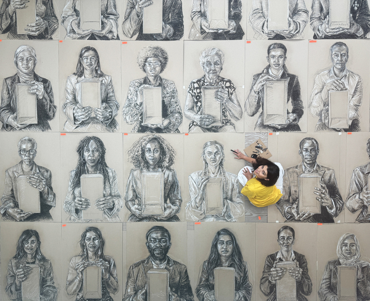 Aerial shot of an artist on top of her charcoal and chalk portraits of people