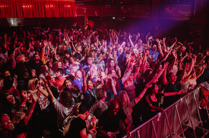 People dancing with their arms in the air on a dancefloor