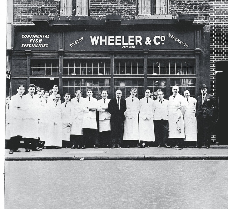 A group of waiters in white aprons outside a chip shop