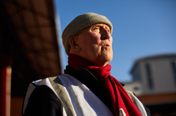 A man wearing a knitted hat and scarf and a steward's vest