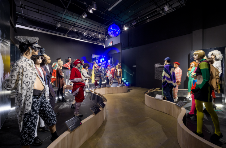 A walkway through an exhibition lined with mannequins wearing different outfits