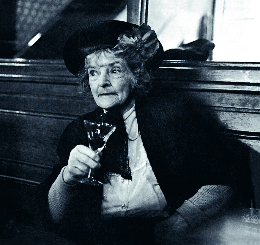 An elderly woman with a glass of booze