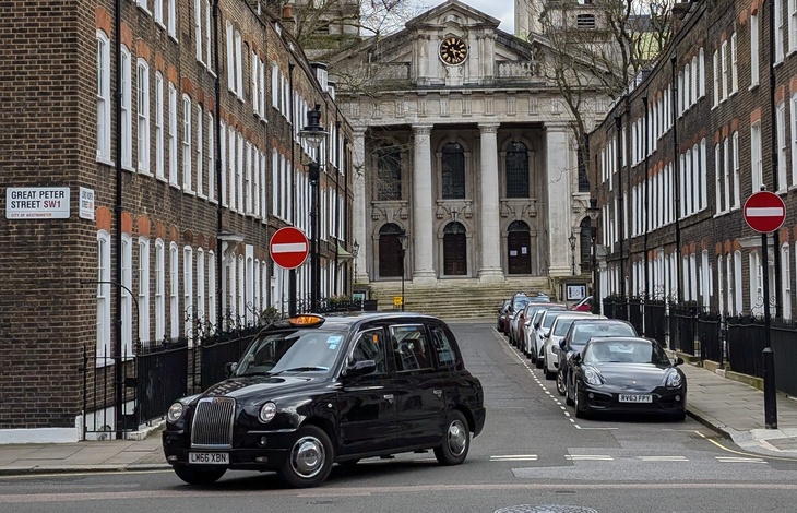 A black cab turning out of a well to do road