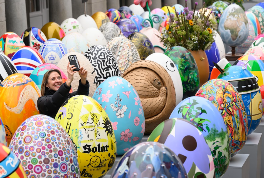 A woman taking a selfie among dozens of colourful eggs