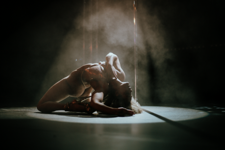 A pole dancer silhouetted in a pose on the floor