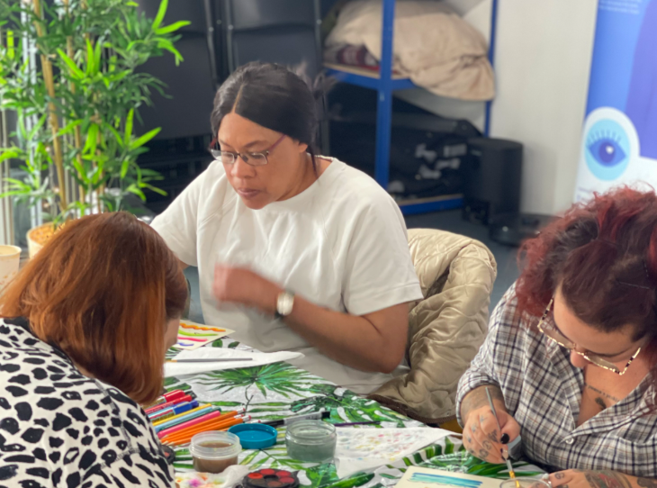 Three adults sitting around a table painting