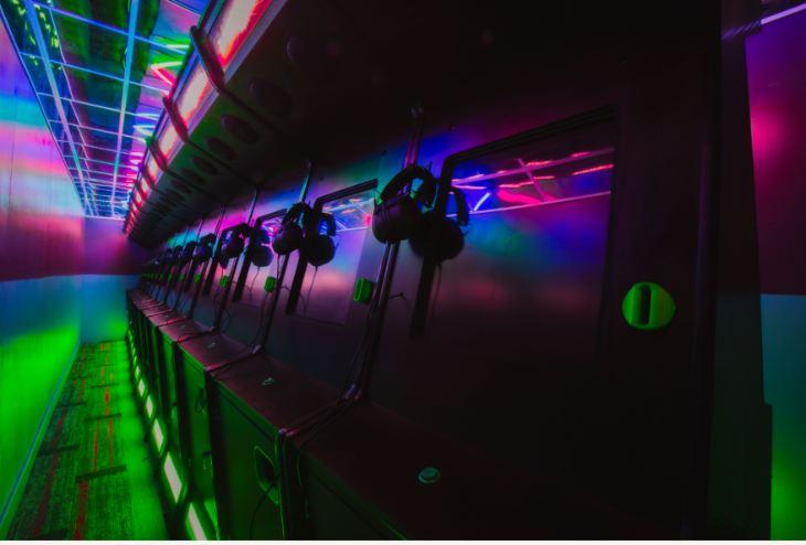 A row of arcade machines lit by eerie coloured lights