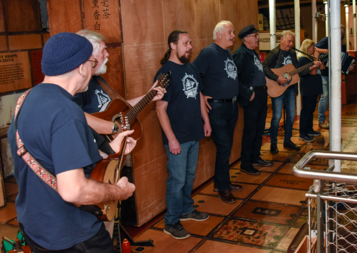 A group of sea shanty singers, some of them holding guitars