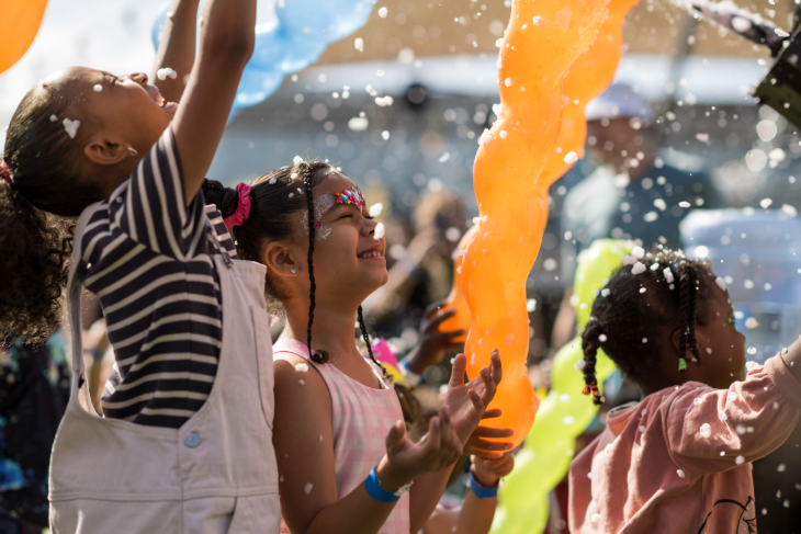 Children with painted faces playing with balloons and bubbles