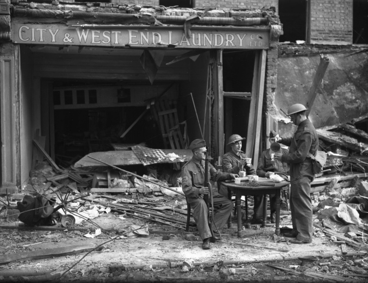 Soldiers taking a break outside a bombed out shop