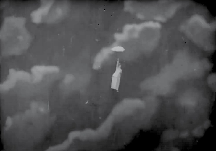 Old film of a woman floating through the skies with an umbrella