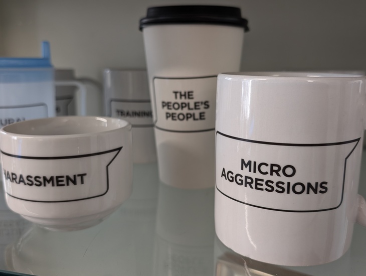 Cups with various things like "micro aggressions" and "Harassment" printed on them