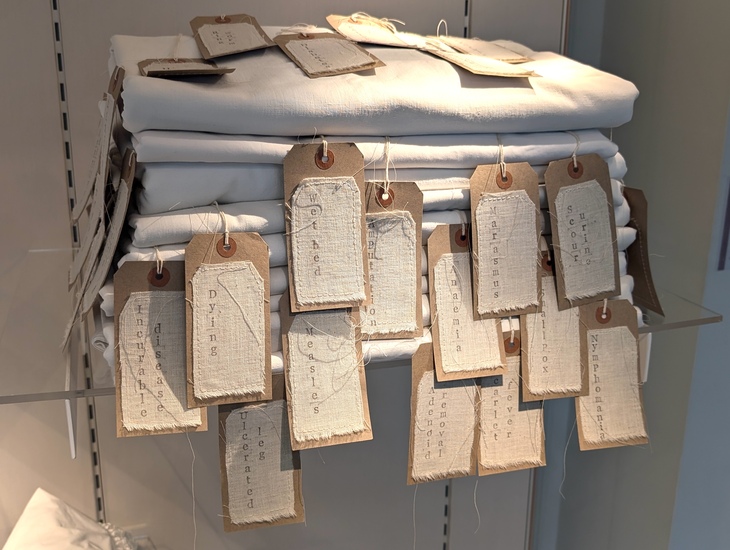 Art installation of folded bedsheets with labels of various maladies