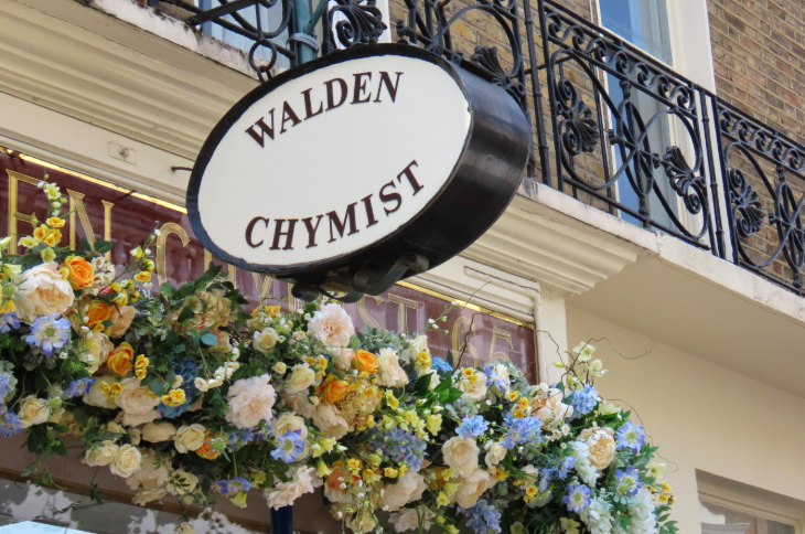 A yellow and blue floral arrangement alongside the hanging sign for 'Walden Chymist'