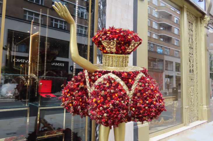 A perfume bottle with legs and arms, made from red flowers