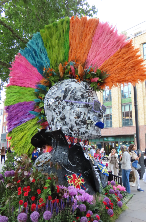 An oversized statue of a punk head, with colourful grasses used to make a mohawk