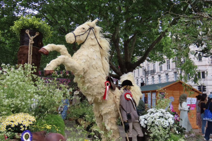 A statue of a white horse, rearing up on two legs, made from plants