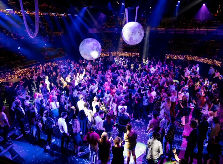 Standing audience members gathered around a central stage