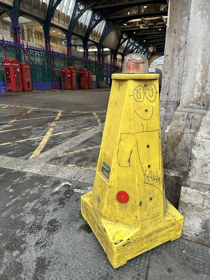 A yellow cone with a robot drawn on it.