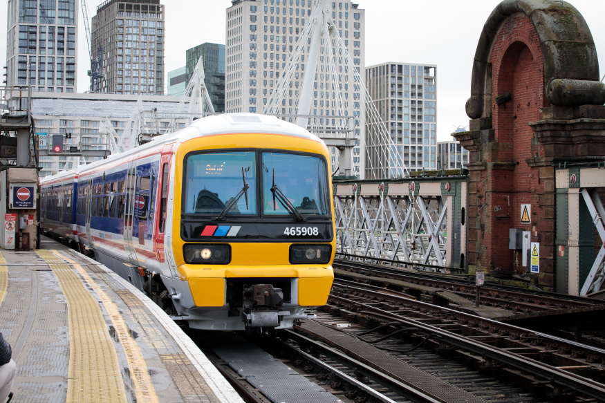 A photograph of a modern train with the blue, red and white livery of Network SouthEast, on the railway bridge at Charing Cross station