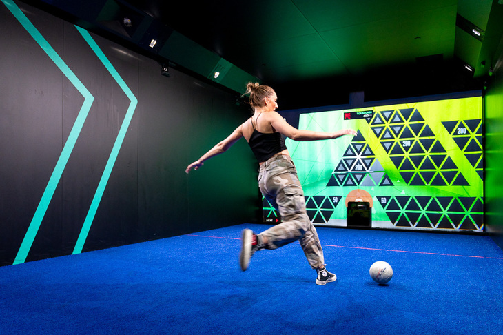 Someone kicking a football in a futuristic looking room