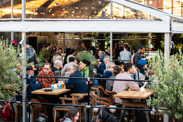 People drinking in a taproom courtyard
