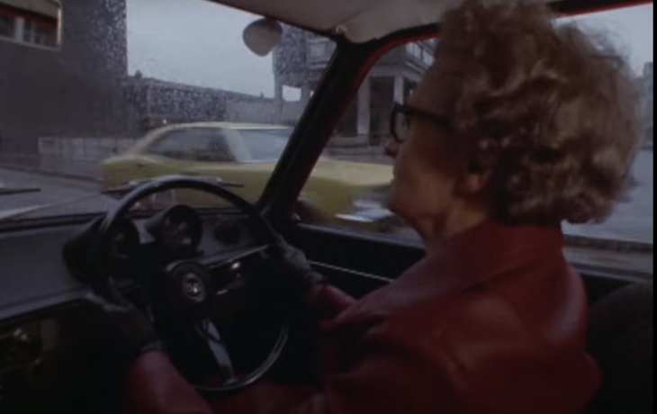 A woman in a red leather coat driving