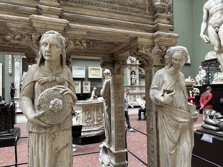 A monument in the v and a with a lady checking her phone