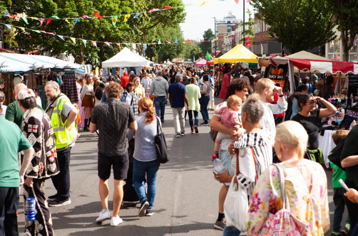 People walking down a road, with stalls on either side