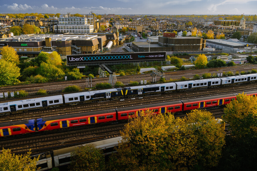 Train passing a really long billboard with an Uber ad on it