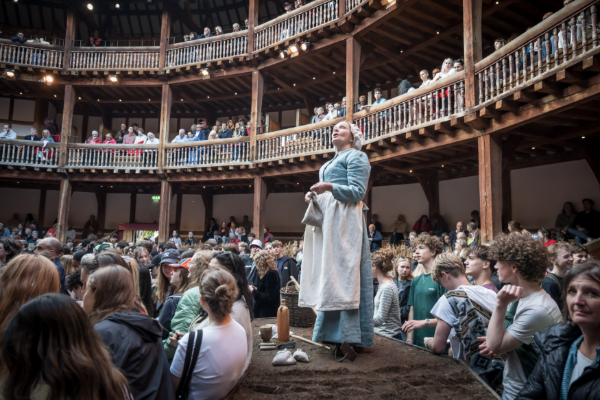 A performer in The Crucible on stage among the crowd at The Globe
