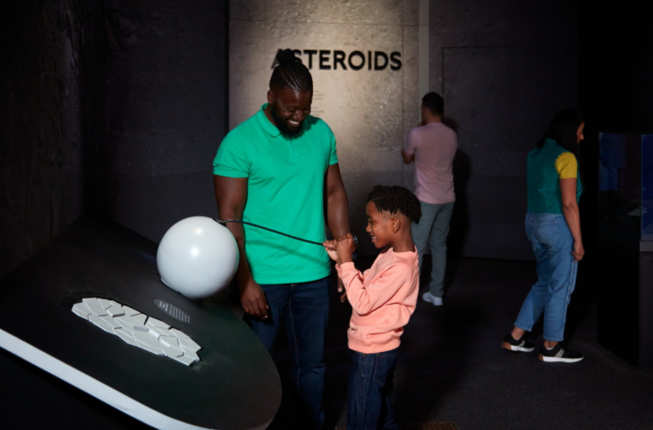 Summer holidays 2025 in London: an adult and child playing with an interactive exhibition at NHM's space exhibition