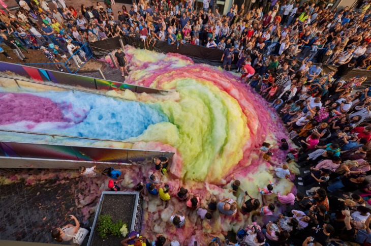 Summer holidays 2025 in London: a crowd surrounding a giant rainbow slide of foam