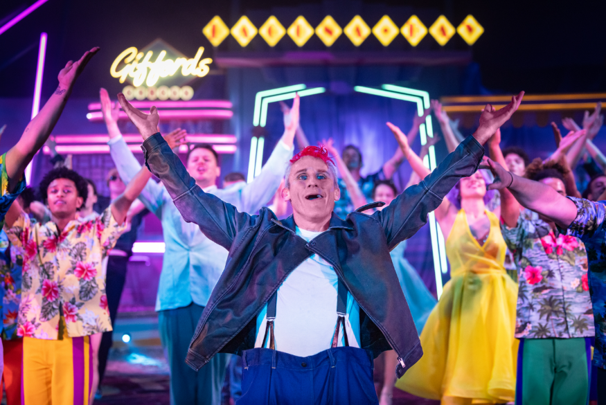 Performers on stage at Gifford's Circus with their arms lifted towards the sky