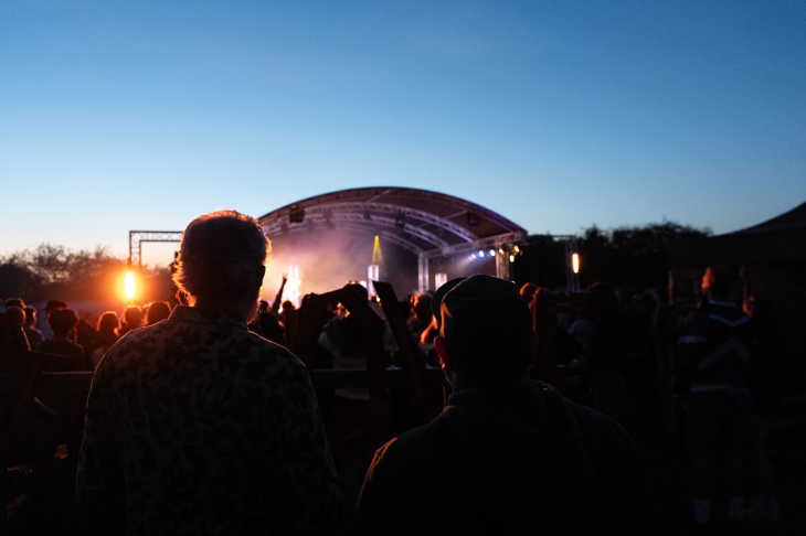 Crowds watching a festival stage at dusk