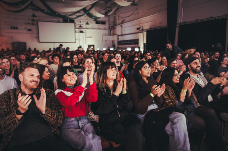 An audience looking forwards and clapping