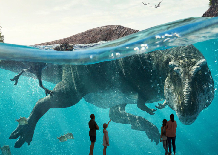 People silhouetted in front of huge screen showing a dinosaur
