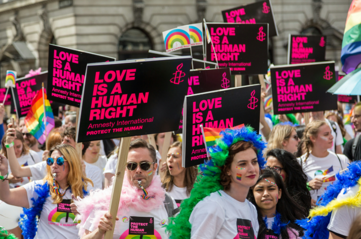 People holding Amnesty International 'Love is a human right' placards at Pride