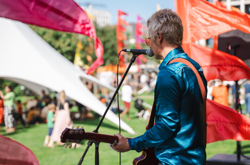 A musician on stage singing and playing guitar