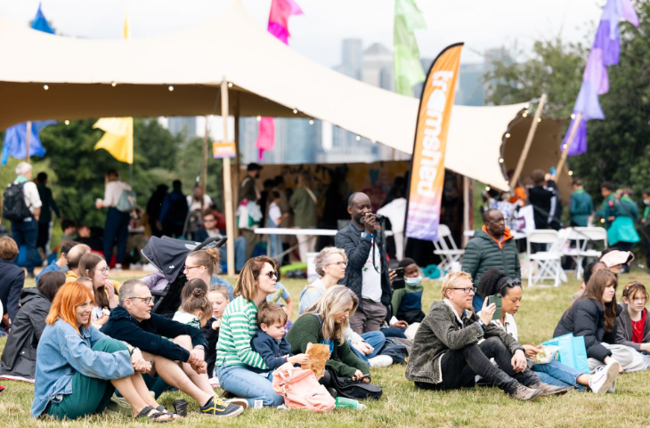 Families sitting on the grass looking towards a stage